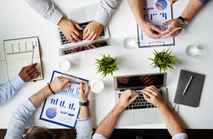 Hands of traders analyzing data at a meeting