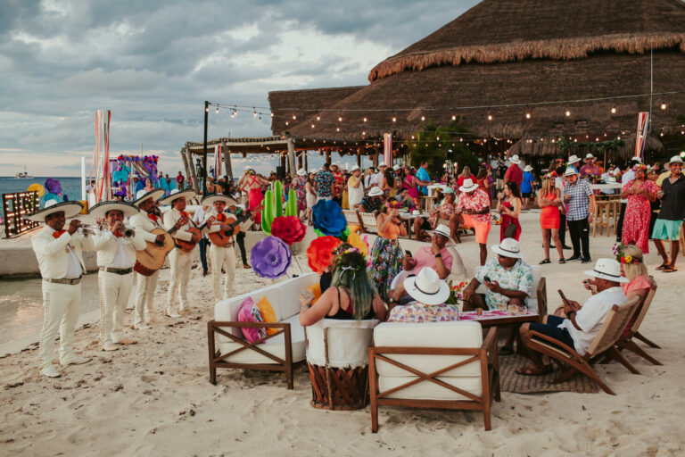 Mariachi band providing entertainment on a beach while people listen and chat with one another