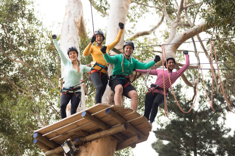 Friends enjoying zip line adventure in park on a sunny day