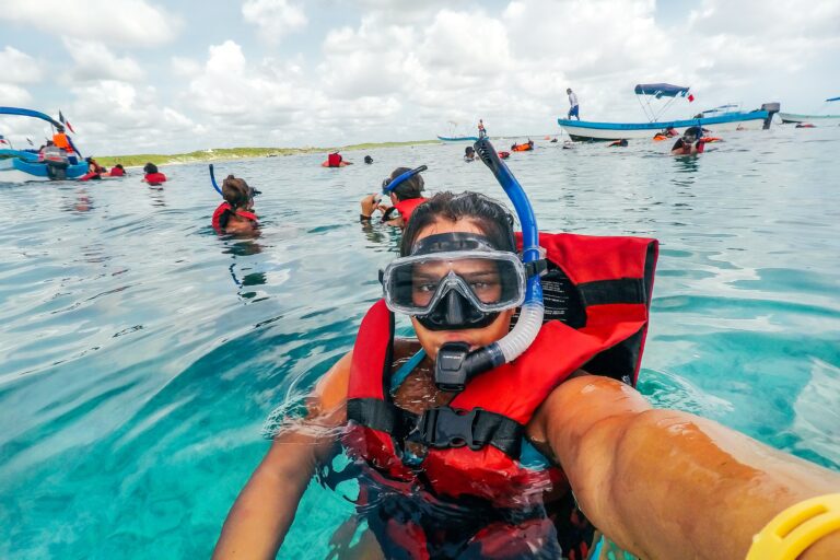 Woman taking a selfie while in clear blue water while wearing a snorkel and life vest