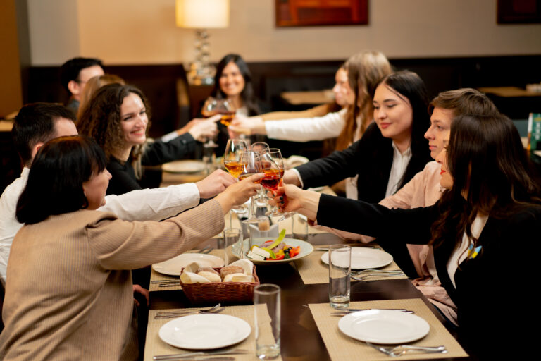 Work colleagues are sitting in a restaurant celebrating the conclusion of new deal toast with glasses of wine