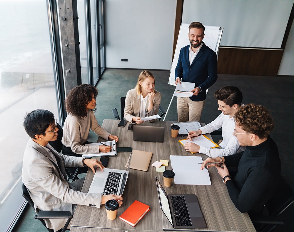 Employees sitting at conference table with laptops