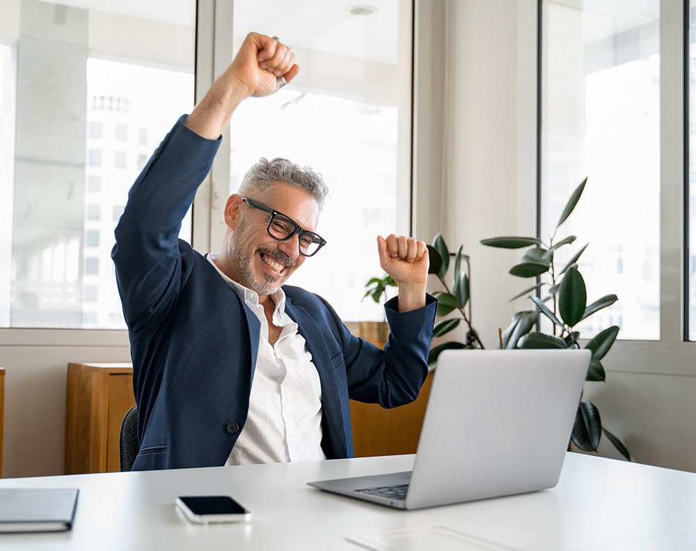 Man celebrating while looking at laptop