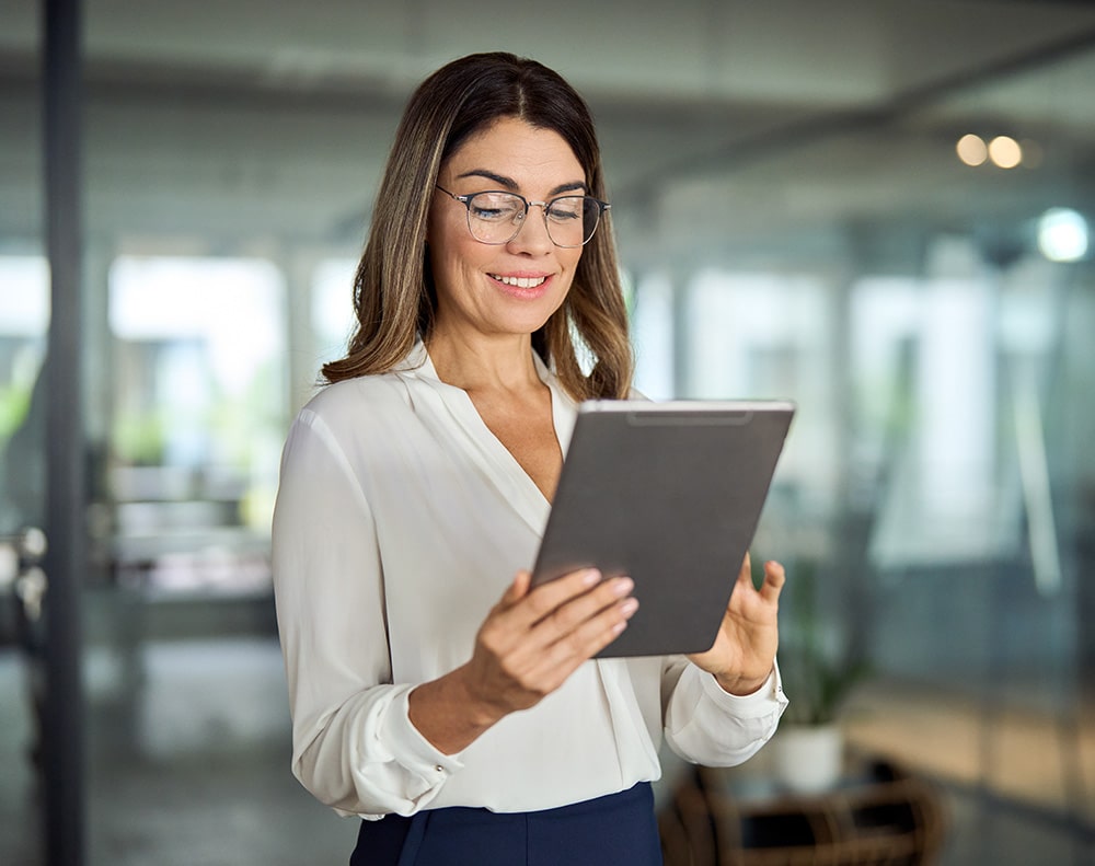 Business woman in her office using a tablet and smiling