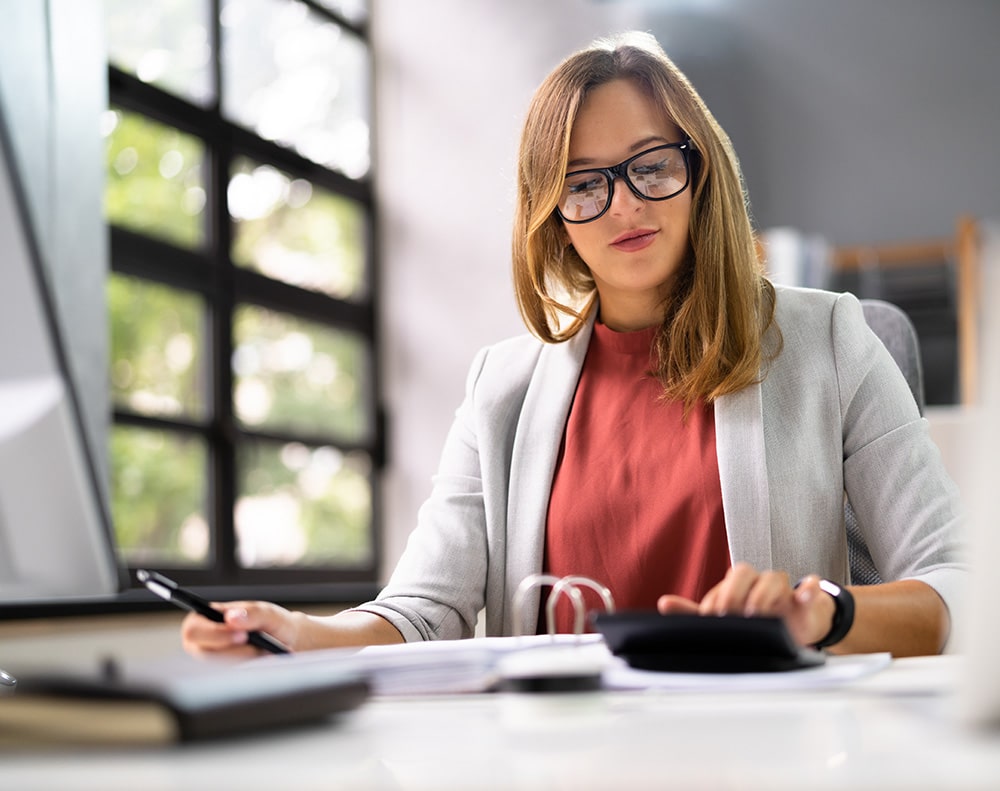 Business woman sitting at a desk using calculator to calculate trip cost