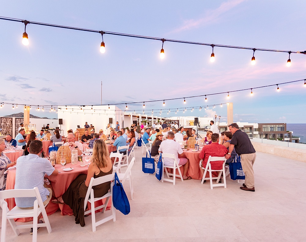 Nicely dressed people seated at tables during a rooftop event