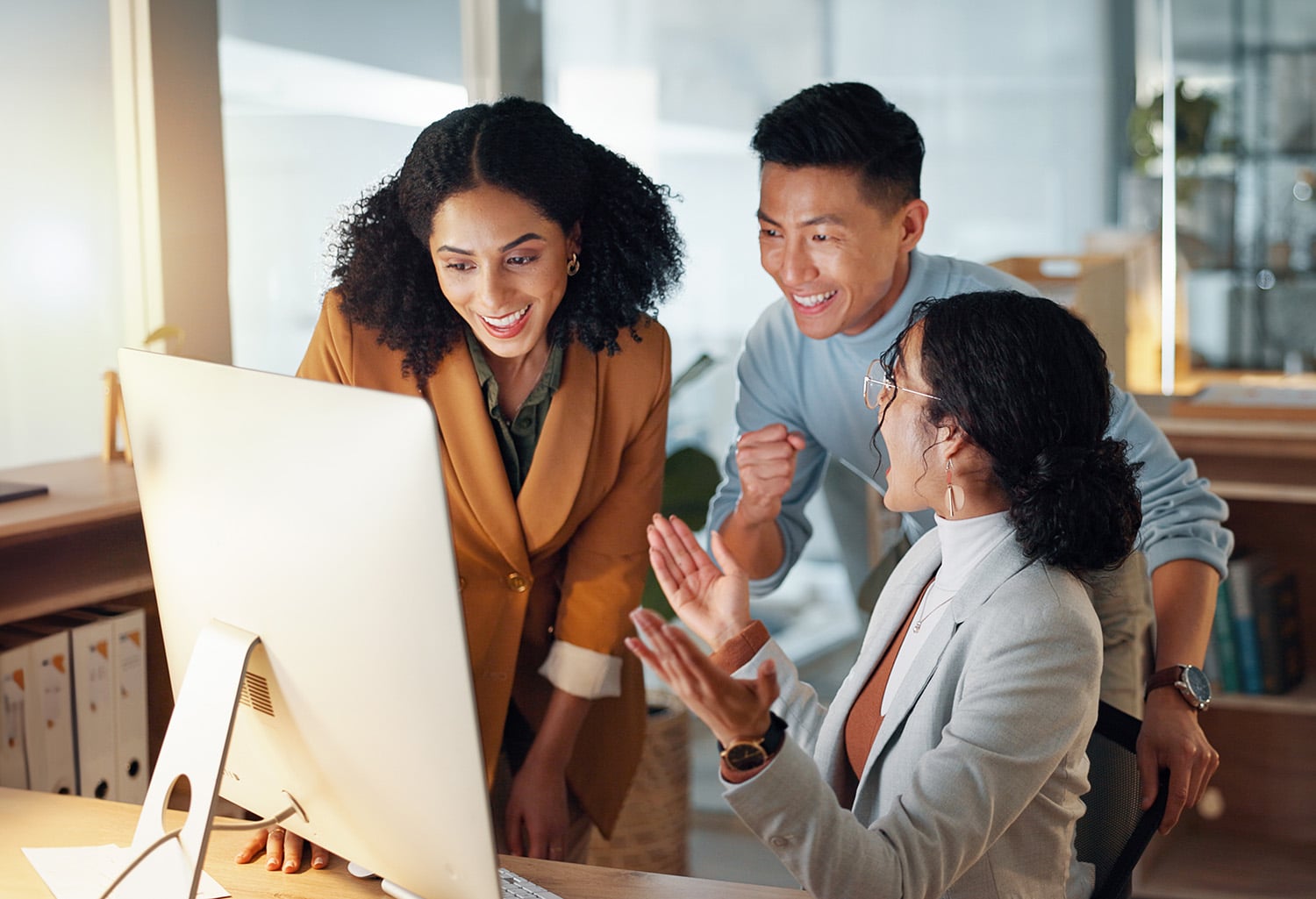 3 coworkers looking excited and celebrating together