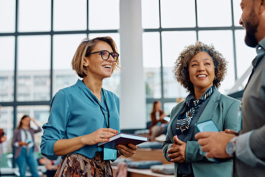 Two women and a man in business dress speaking to one another in a breakout session