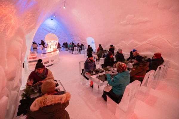 Ice Hotel Dinner_DFMotion Photography Patrons wearing winter clothing dine inside an ice restaurant with tables, chairs, and walls made of ice—a truly unique Incentive Travel to Québec City experience.